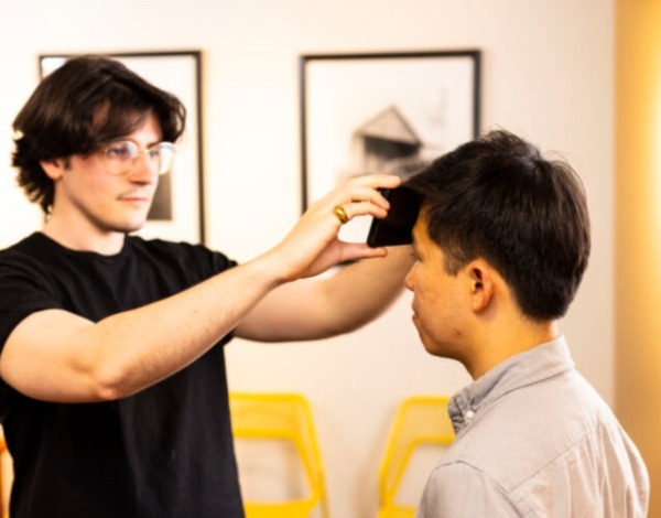 A UW researcher uses a smartphone to test a seated participant's forehead for fever